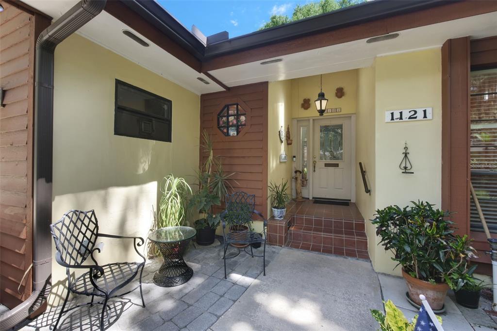 A paved patio area leads to a front entrance with a light-colored door and steps — 1121 SHOREWOOD DRIVE, ORLANDO, FL