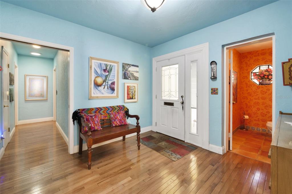 An entryway with light blue walls, hardwood floors, a wooden bench, and an adjacent bathroom — 1121 SHOREWOOD DRIVE, ORLANDO, FL