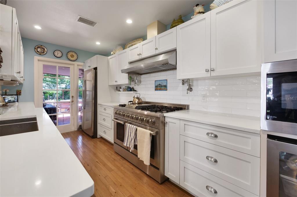 A kitchen features white cabinetry, stainless steel appliances, a gas range, and hardwood flooring — 1121 SHOREWOOD DRIVE, ORLANDO, FL