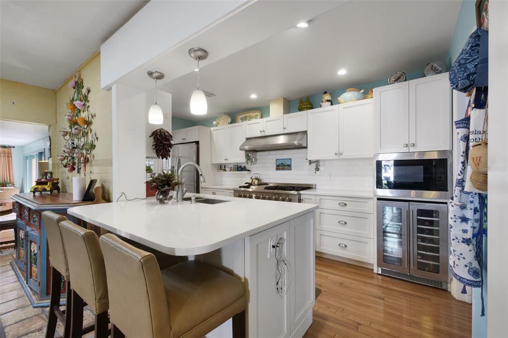 A kitchen features white cabinets, a central island with bar seating, and stainless steel appliances — 1121 SHOREWOOD DRIVE, ORLANDO, FL