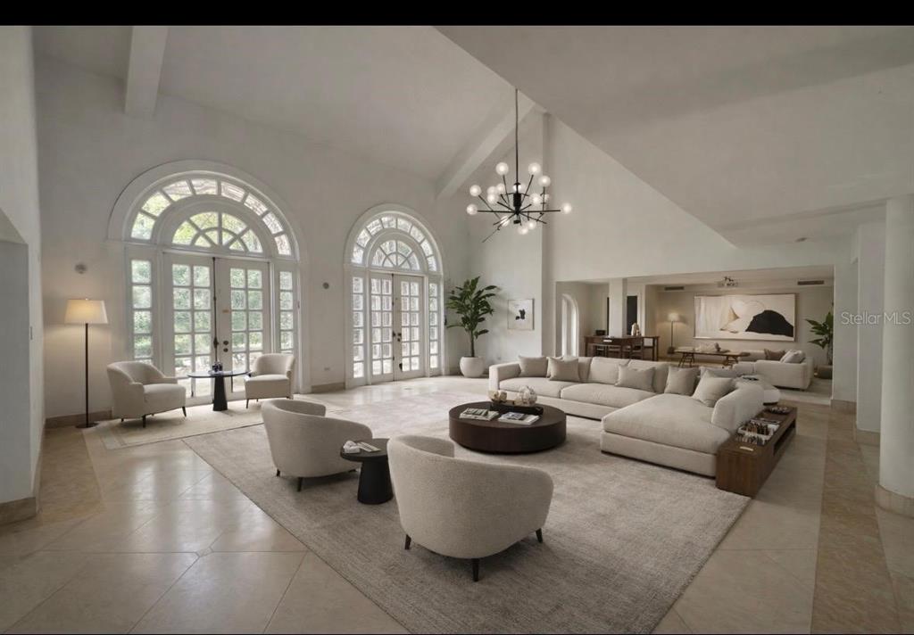A spacious living room features vaulted ceilings, arched glass doors, and neutral modern furniture — Urb. San Patricio RIVERA FERRER ST. UNIT 30, GUAYNABO, PR