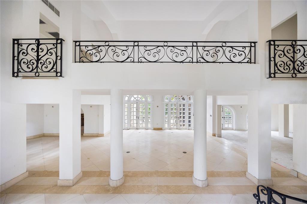A spacious, white-walled interior features a mezzanine with decorative black iron railings and stone flooring — Urb. San Patricio RIVERA FERRER ST. UNIT 30, GUAYNABO, PR
