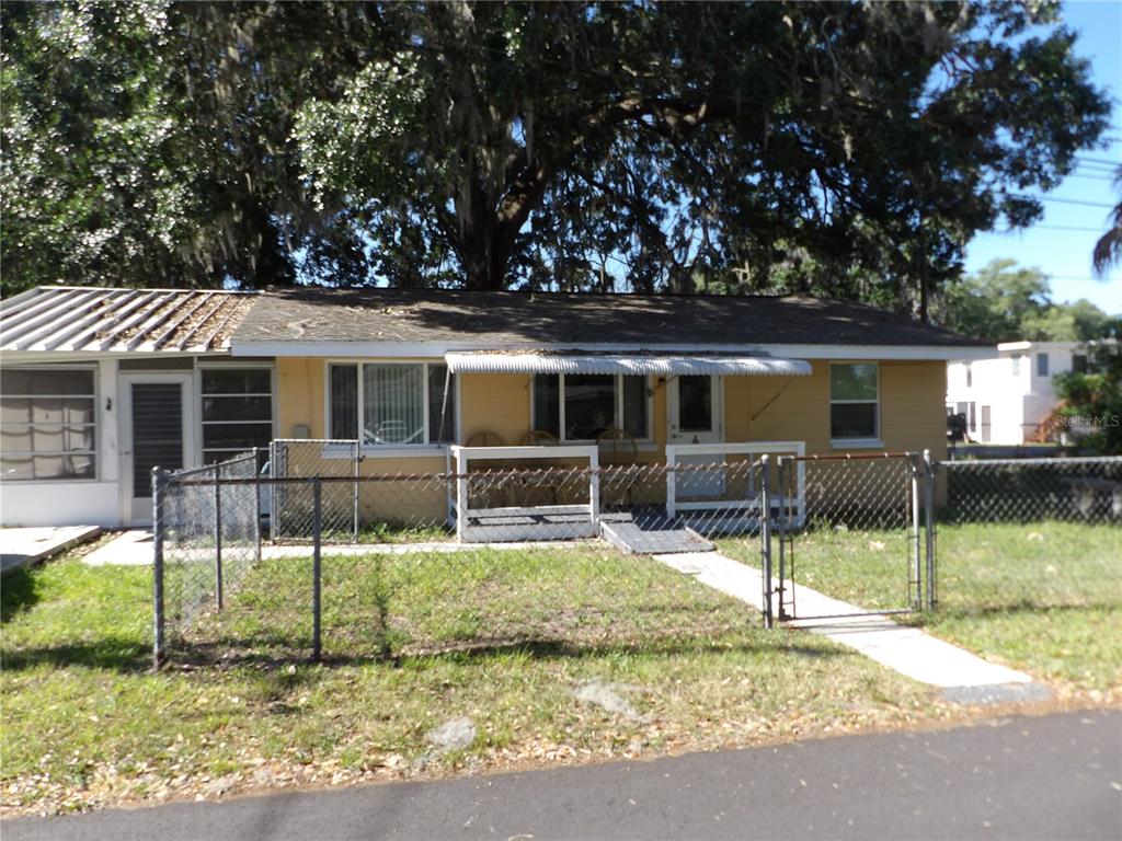 A single-story yellow house with a metal roof and a chain-link fenced front yard — 507 LAKE STREET, INVERNESS, FL