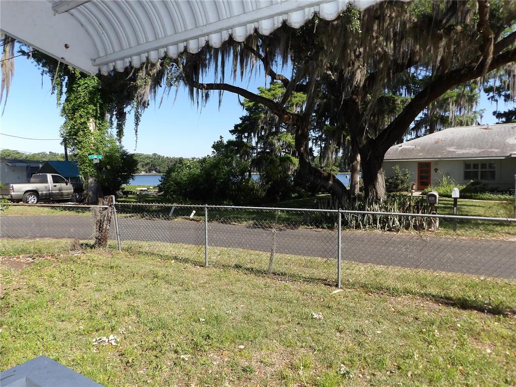 A view from a porch looking across a chain-link fence toward a house and water — 507 LAKE STREET, INVERNESS, FL