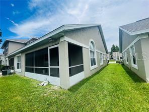 The exterior of a house features a screened-in porch and a grassy side yard — 2206 CYPRESS KNEE LOOP, KISSIMMEE, FL