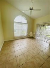 A room with beige tile flooring, a vaulted ceiling, a ceiling fan, and large windows — 2206 CYPRESS KNEE LOOP, KISSIMMEE, FL