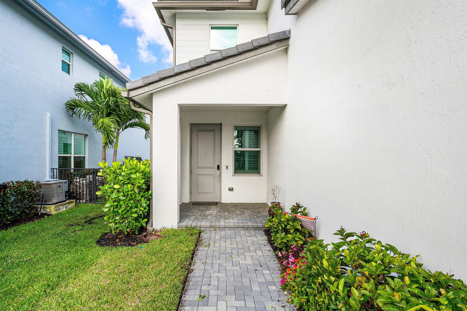 A paved walkway leads to the covered front entrance of a white stucco house — 2659 Country Lake Trail, Boynton Beach FL 33436, BOYNTON BEACH, FL