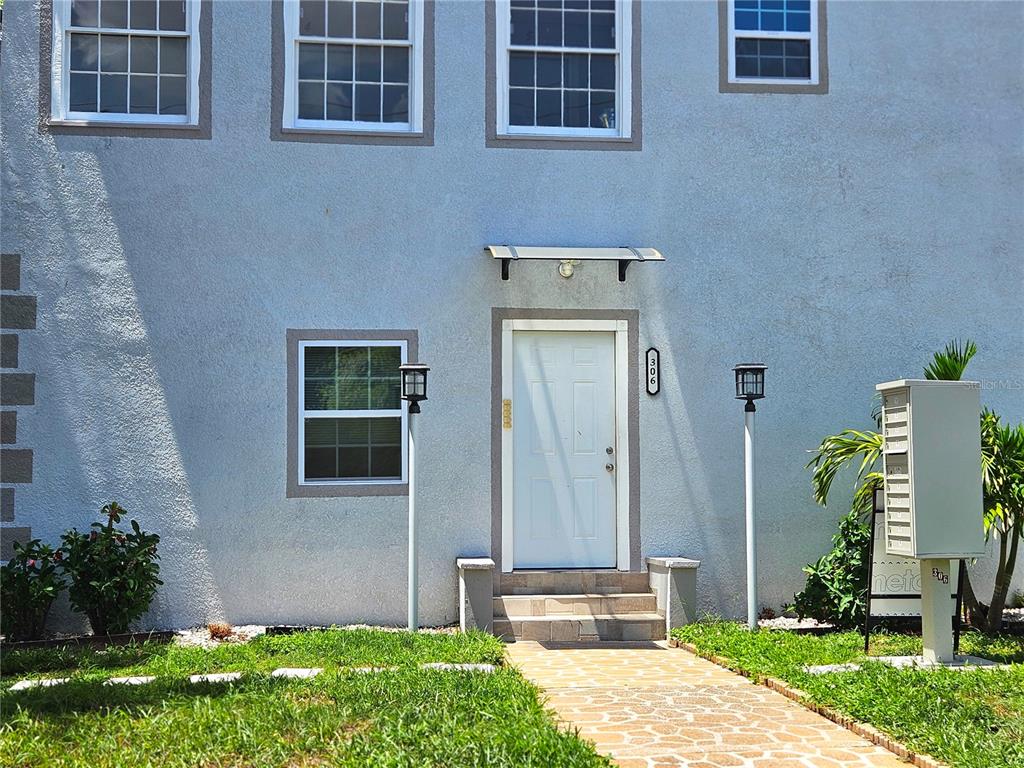 The exterior of a two-story building features a white front door and a stone walkway — 306 TURNER STREET UNIT 1, CLEARWATER, FL