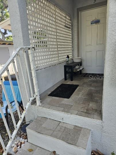 A tiled front porch features a white lattice screen, a small bench, and a front door — 306 TURNER STREET UNIT 1, CLEARWATER, FL