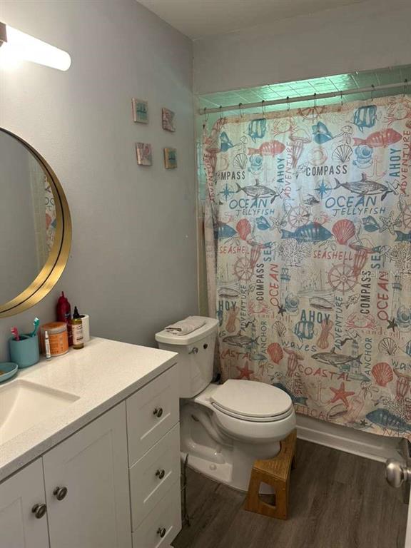 A bathroom features a white vanity, a round mirror, a toilet, and a nautical-themed shower curtain — 1524 MANOR DRIVE, KISSIMMEE, FL