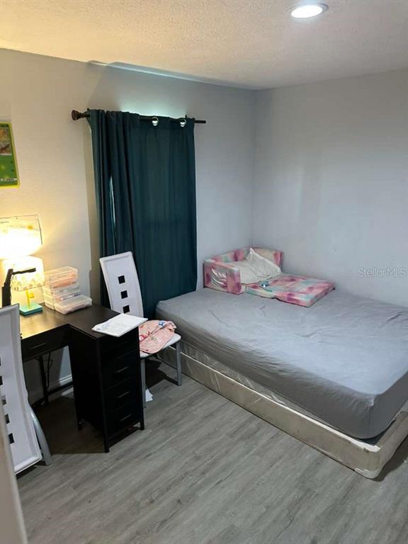 A bedroom features a bed with a gray cover, a desk, and a dark curtain — 1524 MANOR DRIVE, KISSIMMEE, FL