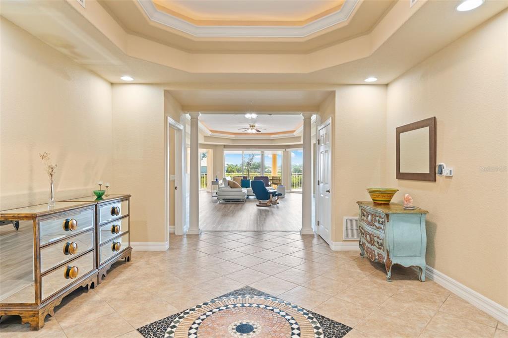 A tiled foyer features a decorative floor medallion, two console tables, and a tray ceiling — 6100 JESSIE HARBOR DRIVE UNIT 202, OSPREY, FL