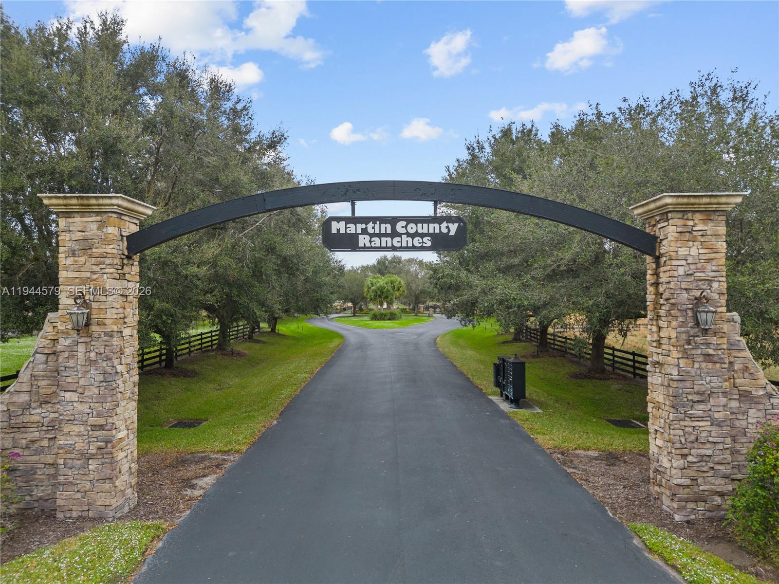 A stone-pillared gate marks the entrance to a paved driveway lined with trees — 25750 SW Jockeys Run, Okeechobee FL 34974, OKEECHOBEE, FL