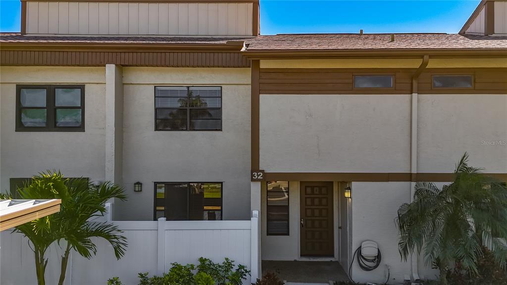 The exterior of a two-story townhouse features a brown front door and white fencing — 9209 SEMINOLE BOULEVARD UNIT 32, SEMINOLE, FL