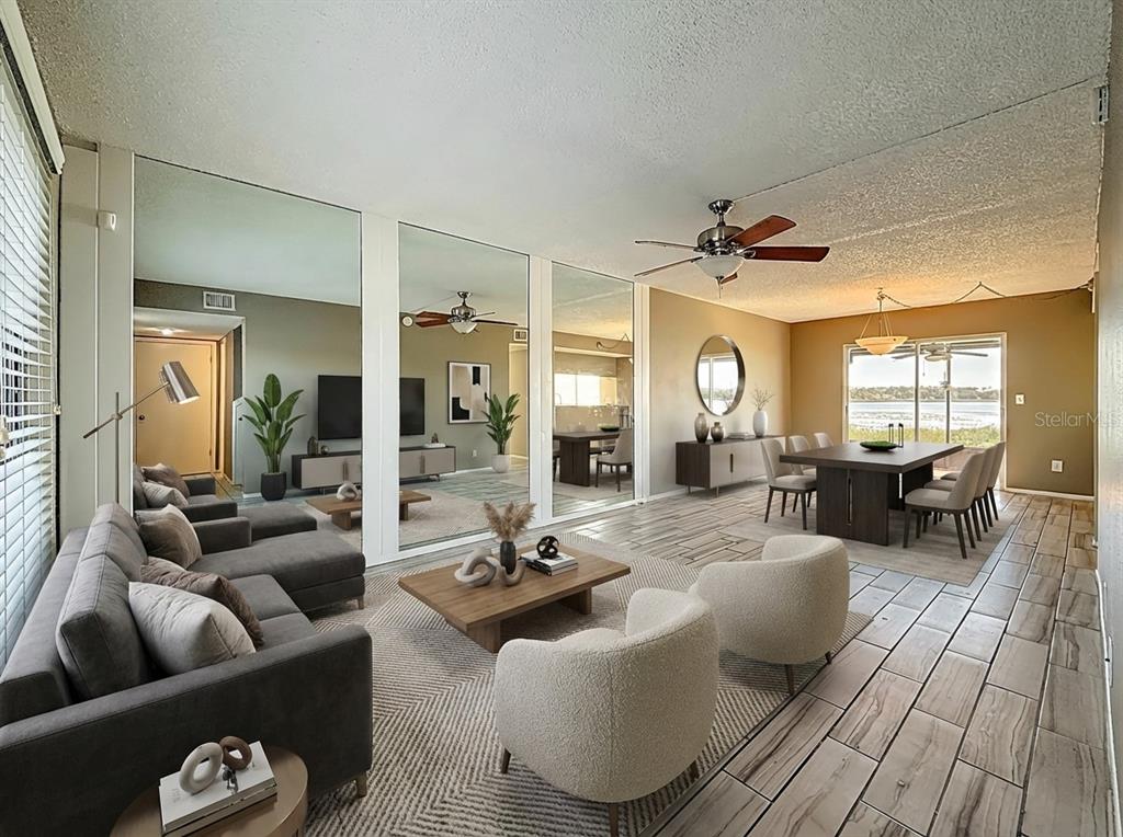 A living and dining area with mirrored walls, wood-look tile floors, and a water view — 9209 SEMINOLE BOULEVARD UNIT 32, SEMINOLE, FL