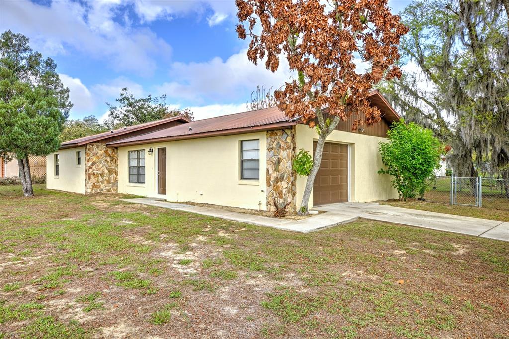 A single-story house with a metal roof, stone accents, and an attached garage — 2052 W STRYKER ROAD, AVON PARK, FL