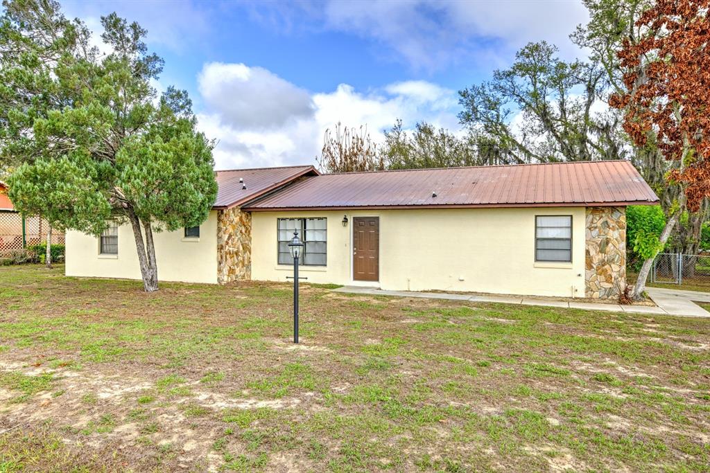 A single-story house with a metal roof, stone accents, and a brown front door — 2052 W STRYKER ROAD, AVON PARK, FL