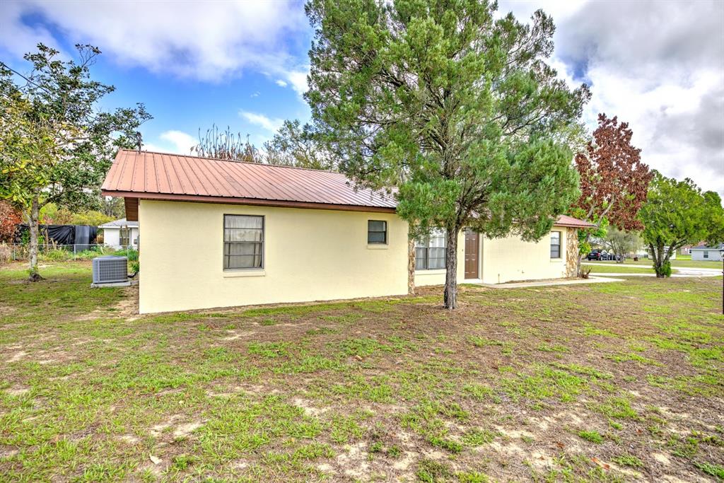 A single-story house with a metal roof and light-colored stucco exterior sits on a lawn — 2052 W STRYKER ROAD, AVON PARK, FL