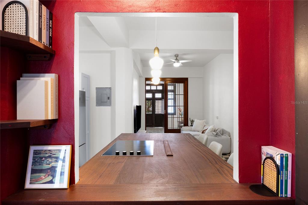 A wooden kitchen island with a cooktop overlooks a living room through a red wall — 360-362 FORTALEZA UNIT 7, SAN JUAN, PR