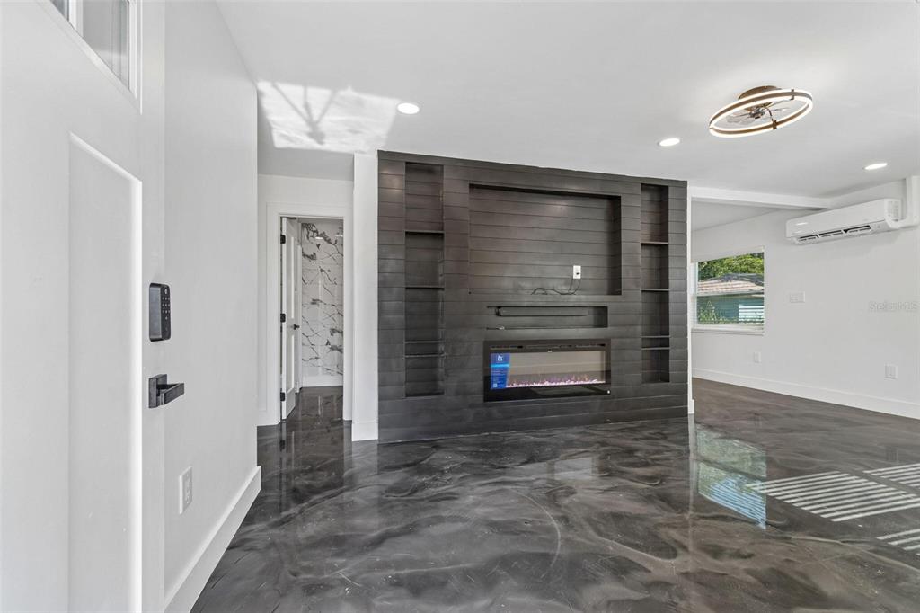 A living room features a dark wood accent wall with a fireplace and glossy flooring — 4125 GROVE, ST PETERSBURG, FL