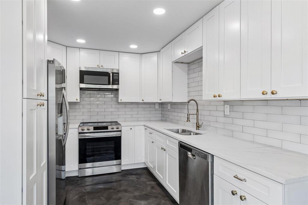 A kitchen features white cabinets, stainless steel appliances, a light countertop, and a gray backsplash — 4125 GROVE, ST PETERSBURG, FL