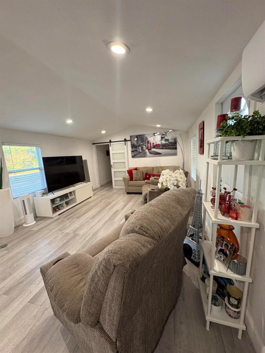 A living room features light wood-look flooring, a television, and two beige sofas — 855 N Datil Street, Clewiston FL 33440, CLEWISTON, FL
