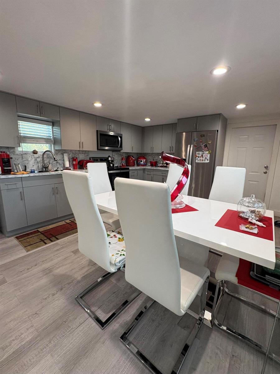 A kitchen and dining area with gray cabinets, white chairs, and a white dining table — 855 N Datil Street, Clewiston FL 33440, CLEWISTON, FL