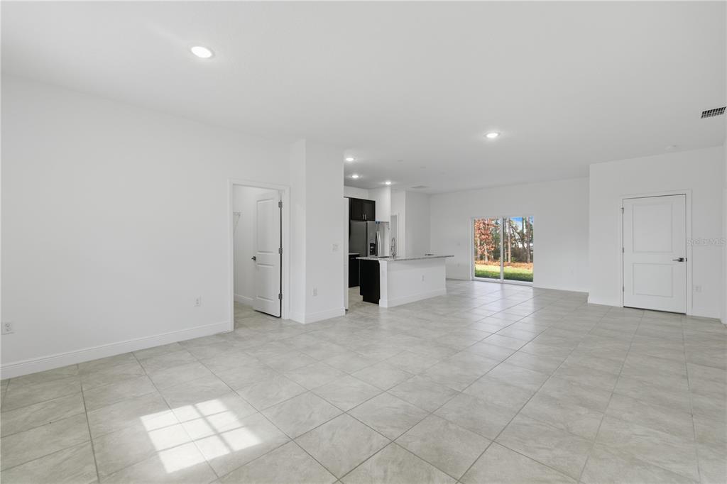 An open-concept living area features light tile flooring, white walls, and a kitchen with an island — 15936 SW 35TH COURT ROAD, OCALA, FL