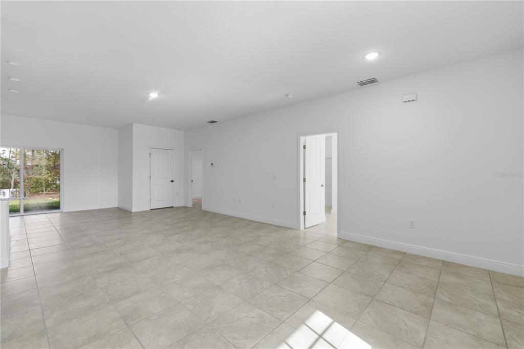 An empty room with light-colored tile flooring, white walls, and a sliding glass door — 15936 SW 35TH COURT ROAD, OCALA, FL