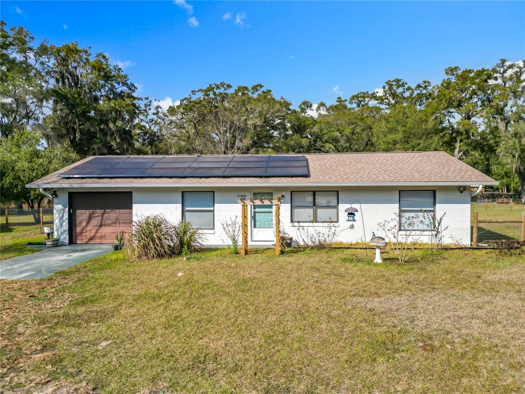A white house with a screened porch sits on a large, fenced grassy lot — 11859 W HIGHWAY 328, OCALA, FL
