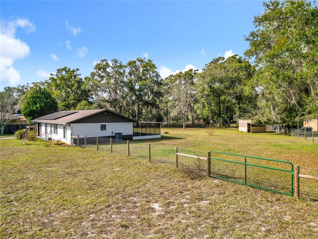 An aerial view shows a rural property with multiple buildings, fenced yards, and surrounding trees — 11859 W HIGHWAY 328, OCALA, FL
