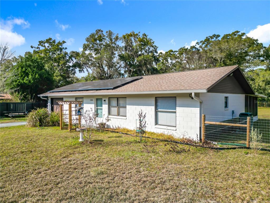 A white concrete block house features a wooden arbor over the front entrance — 11859 W HIGHWAY 328, OCALA, FL