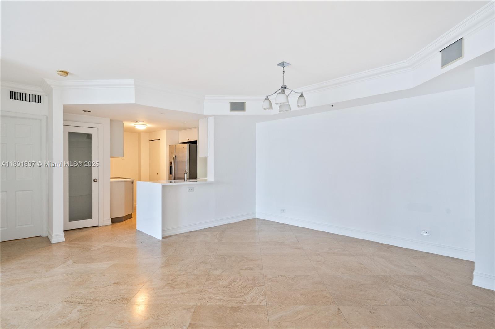 An open-concept living and dining area features beige tile flooring and a white kitchen — 701 Brickell Key Blvd # 1411, Miami FL 33131, MIAMI, FL