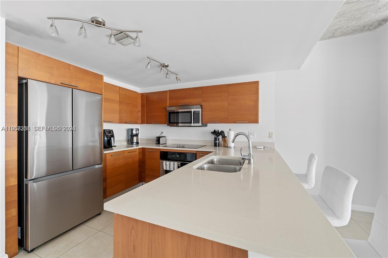 A modern kitchen features wood cabinets, stainless steel appliances, and a white quartz island — 3250 NE 1st Ave # 917, Miami FL 33137, MIAMI, FL