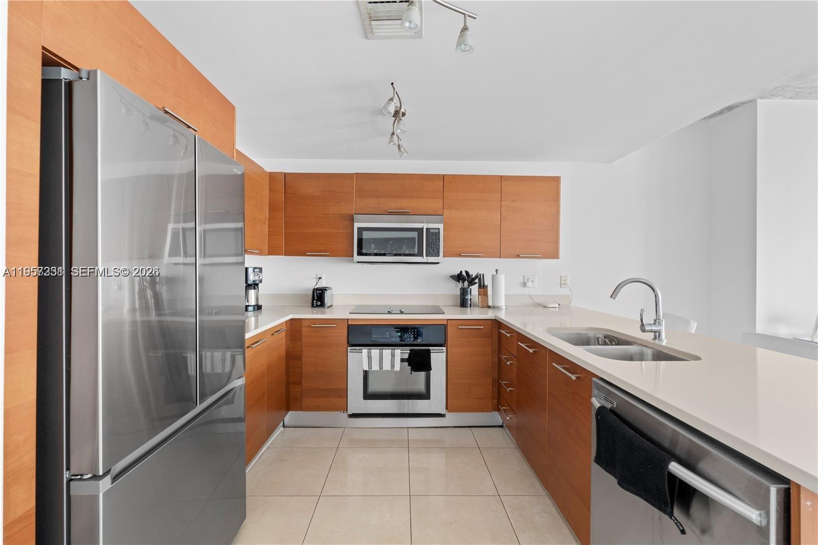 A modern kitchen features wood cabinets, stainless steel appliances, and light-colored countertops — 3250 NE 1st Ave # 917, Miami FL 33137, MIAMI, FL