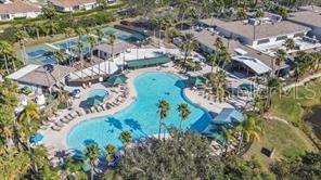 An aerial view shows a community swimming pool surrounded by lounge chairs, palm trees, and buildings — 1811 BEDFORD LANE UNIT 164, SUN CITY CENTER, FL