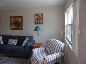 A living room features a blue sofa, a striped armchair, and two framed floral pictures — 1811 BEDFORD LANE UNIT 164, SUN CITY CENTER, FL