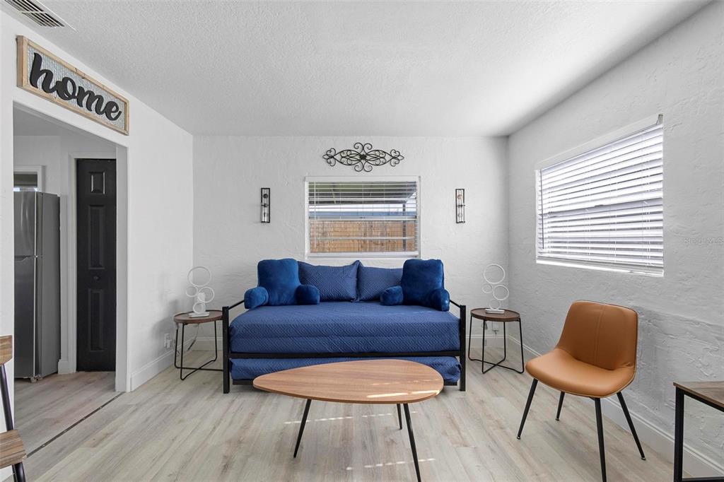 A living room features a blue daybed, a wooden coffee table, and a tan chair — 2600 S CRYSTAL LAKE DRIVE, ORLANDO, FL