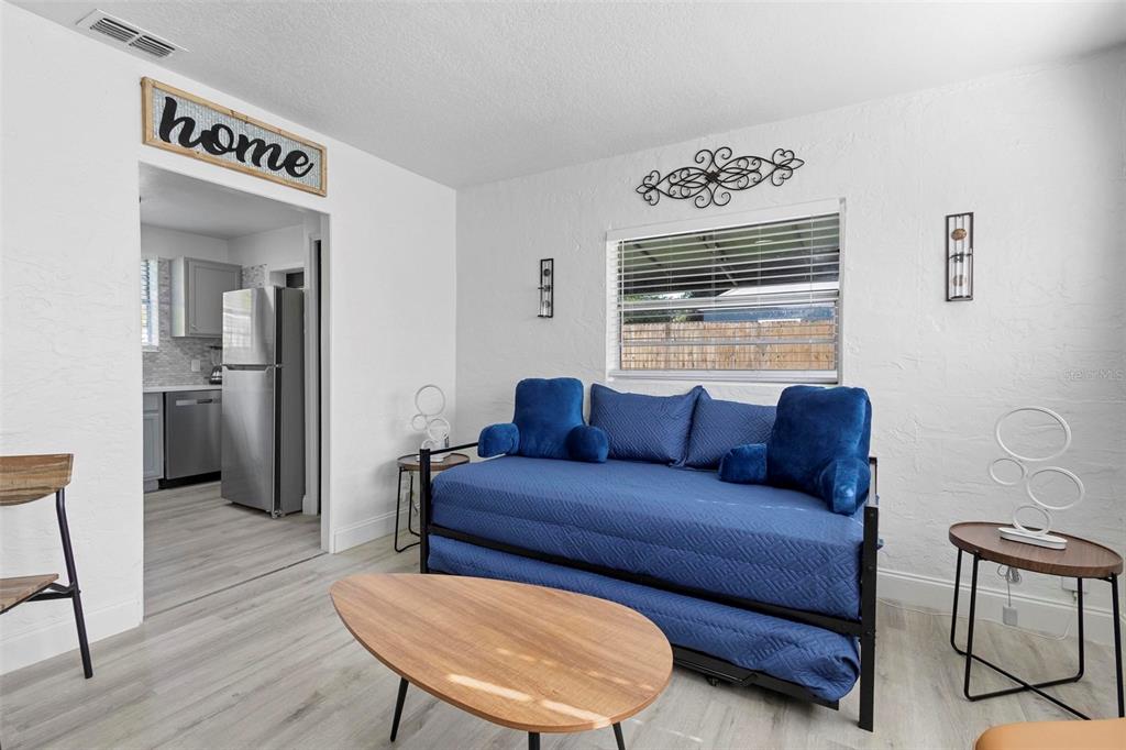 A living room features a blue daybed, a wooden coffee table, and a kitchen doorway — 2600 S CRYSTAL LAKE DRIVE, ORLANDO, FL