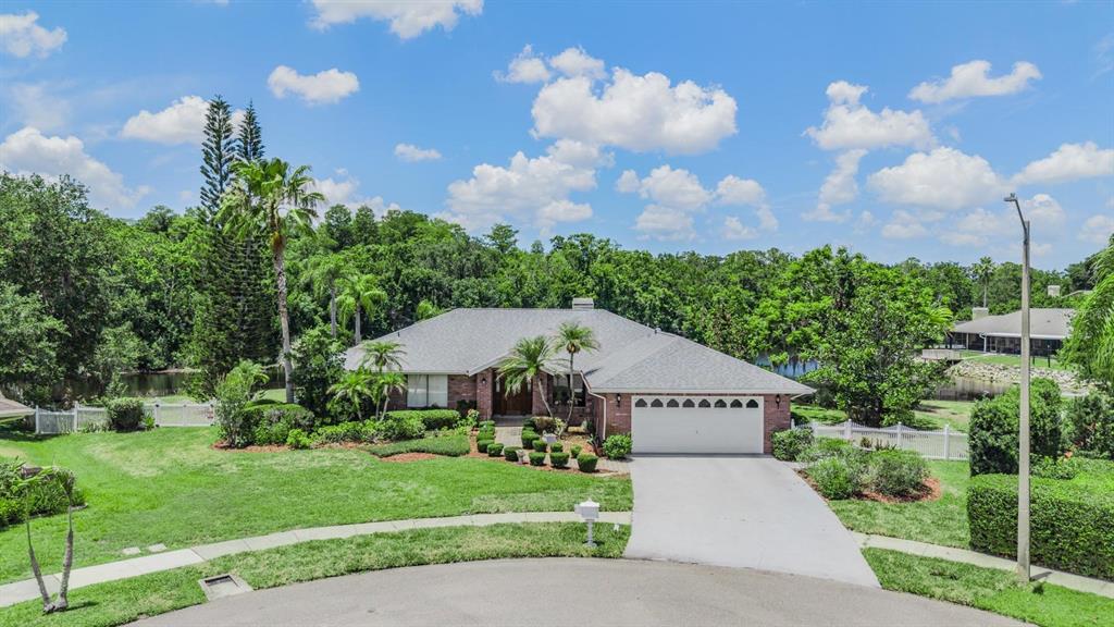 A single-story brick house with a white garage and a large lawn faces a street — 3817 NICHOLAS CIRCLE, TARPON SPRINGS, FL