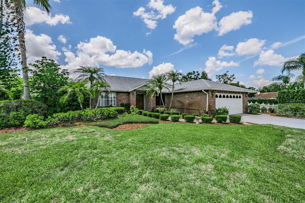 A single-story brick house with a front lawn, palm trees, and a two-car garage — 3817 NICHOLAS CIRCLE, TARPON SPRINGS, FL