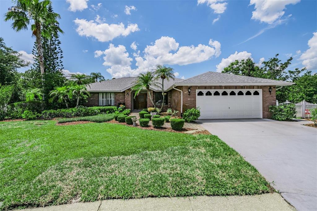 A single-story brick house with a two-car garage and a landscaped front yard — 3817 NICHOLAS CIRCLE, TARPON SPRINGS, FL