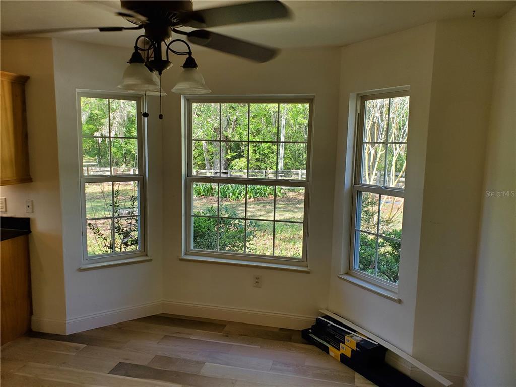 A dining nook features a ceiling fan, three windows overlooking a yard, and wood-look flooring — 22819 NW 209TH TERRACE, HIGH SPRINGS, FL