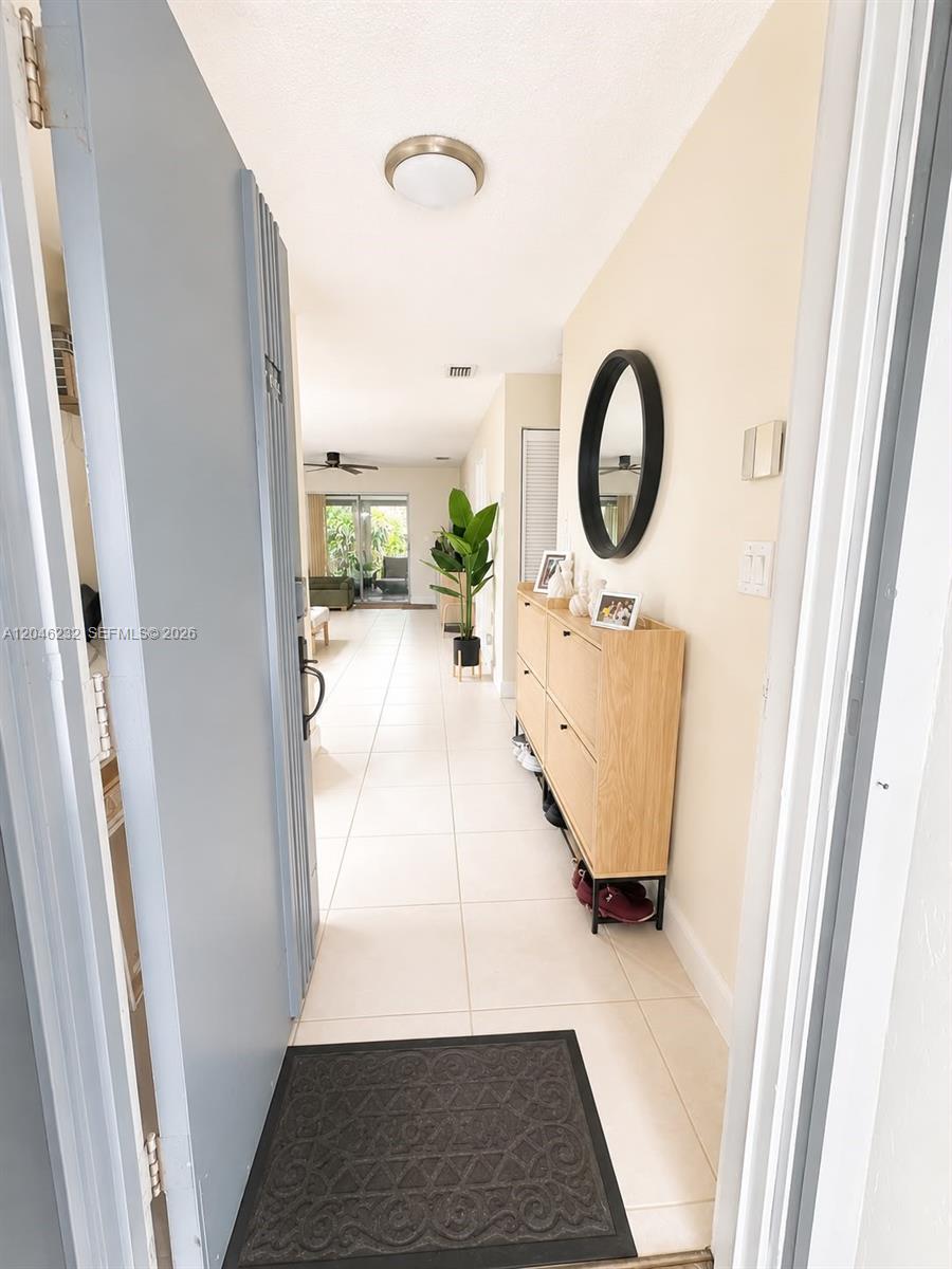 An entryway with light tile flooring leads into a living area with a sliding door — 7954 NW 41st Ct, Sunrise FL 33351, SUNRISE, FL