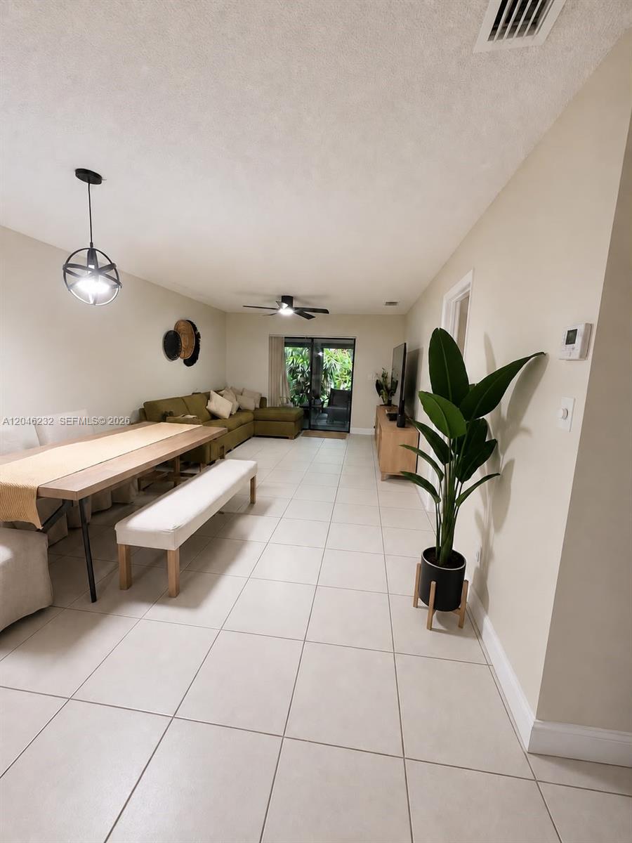 This open-concept living and dining area features tile flooring, a dining table, and a sectional — 7954 NW 41st Ct, Sunrise FL 33351, SUNRISE, FL