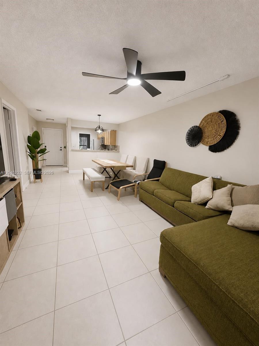 This open-concept living and dining area features tile flooring, a green sectional, and a ceiling fan — 7954 NW 41st Ct, Sunrise FL 33351, SUNRISE, FL