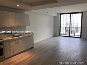 A modern kitchen with light wood cabinets opens into a living area with floor-to-ceiling windows — 55 SW 9th St # 2504, Miami FL 33130, MIAMI, FL