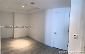 An empty room with light wood-look flooring and a white door — 55 SW 9th St # 2504, Miami FL 33130, MIAMI, FL
