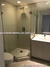A modern bathroom features a glass-enclosed corner shower, a light wood vanity, and a toilet — 55 SW 9th St # 2504, Miami FL 33130, MIAMI, FL