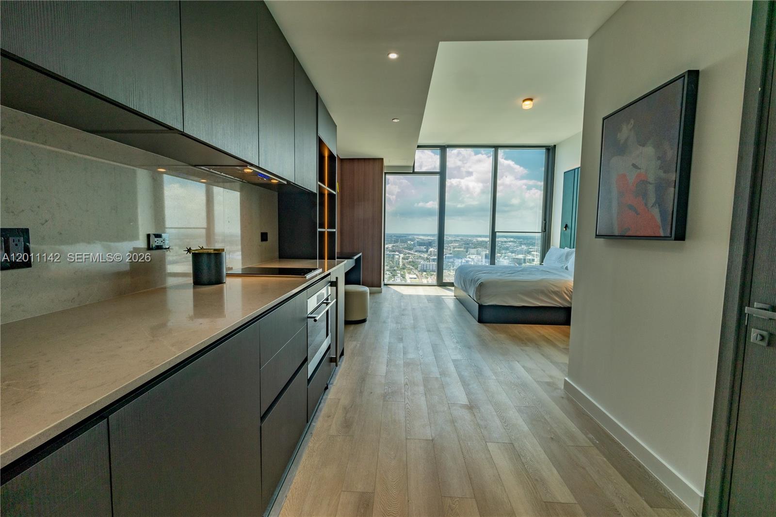 A modern studio apartment features a sleek kitchen, light wood flooring, and floor-to-ceiling windows — 20 NE 11th st # 5306, Miami FL 33132, MIAMI, FL